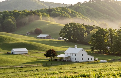 Arkansas Ozark Mountain farmland with white farmhouse and poultry barns in the valley
