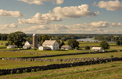 Augusta Maine area countryside with a classic white dairy farm with silos surrounded by green pastures along the Kennebec River valley