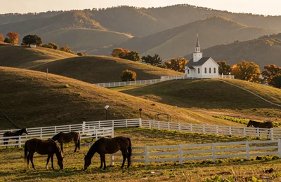 Tennessee horse farm with white fences and country church on rolling hills near Smoky Mountains