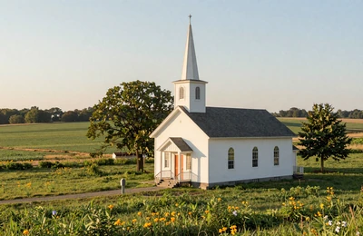 Christian country church with white steeple surrounded by green farmland in the rural Midwest
