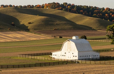 Missouri Ozarks farmland with rolling pastures and a classic white barn near the Kansas border