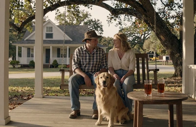 Farmer couple on a Southern farmhouse porch swing at sunset with sweet tea and a golden retriever