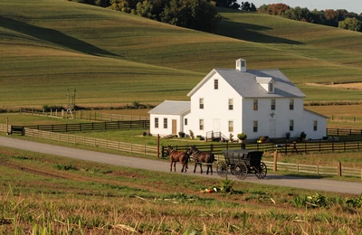 Ohio Amish country farmland with rolling green hills and white farmhouse near Indiana border