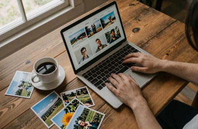 Person creating a farmer dating profile on a laptop at a rustic farmhouse table with coffee